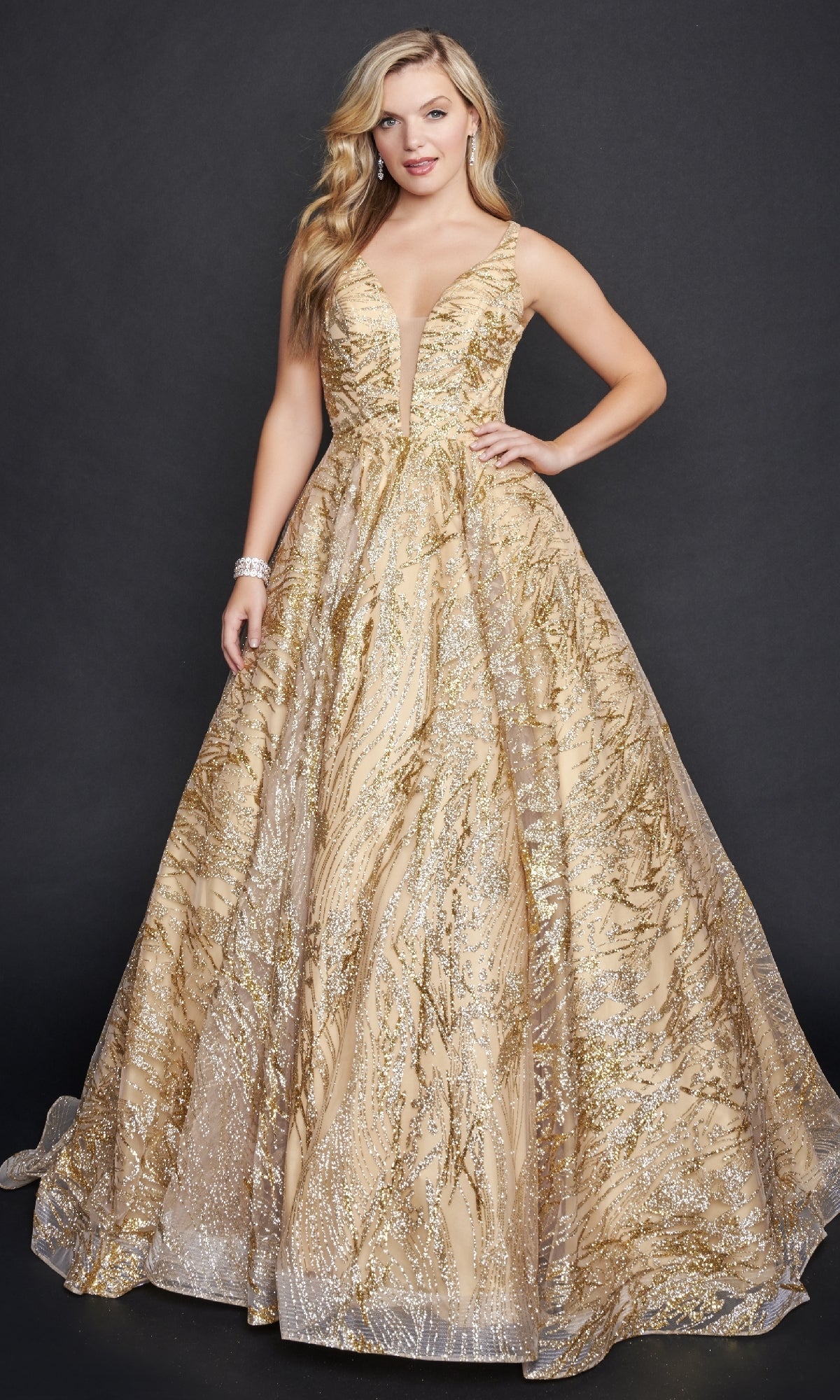 A woman wears the Nina Canacci 8209 Print Prom Ball Gown, a sleeveless gold and silver glitter dress with a deep V-neckline, standing against a plain dark background.